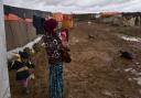 A Syrian refugee holds her daughter at an informal tented settlement near the Syrian border, on the outskirts of Mafraq, Jordan