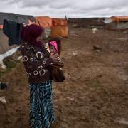 A Syrian refugee holds her daughter at an informal tented settlement near the Syrian border, on the outskirts of Mafraq, Jordan