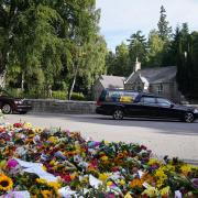 The hearse carrying the coffin of Queen Elizabeth II, draped with the Royal Standard of Scotland, leaving Balmoral as it begins its journey to Edinburgh. Picture date: Sunday September 11, 2022.