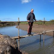 The National Trust has submitted plans to rebuild a bridge over Stiffkey marshes which it removed more than two years ago. Pictured is Stiffkey resident Ian Curtis on a makeshift bridge over the creek