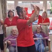 Chloe Lawlor leads a singing celebration to Leon Mallet's 'Let's Be Avin You' at a north Norfolk care home.